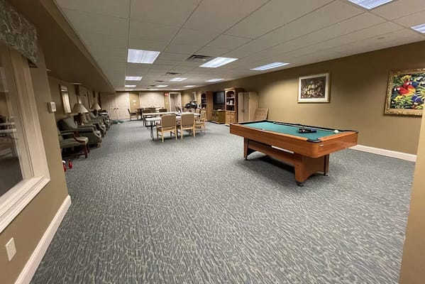 A spacious recreational room with a pool table and seating areas.