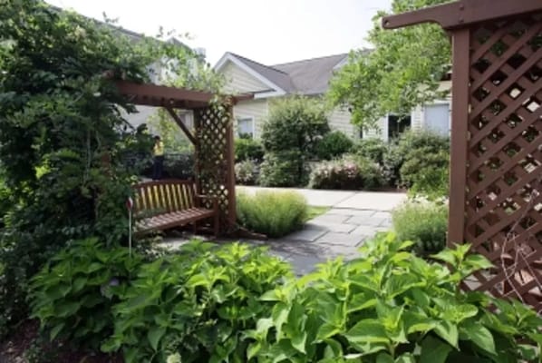 Garden seating area with a wooden swing and lush greenery