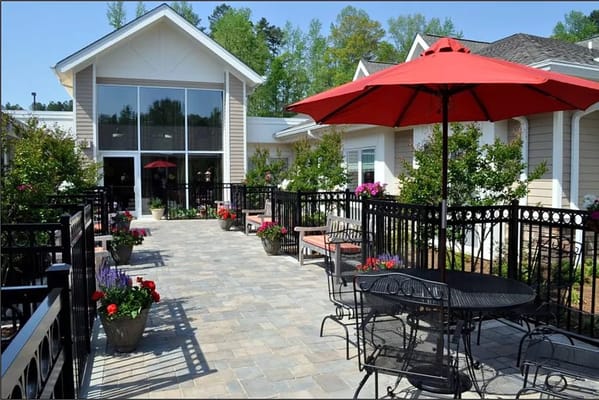 A patio area with tables, chairs, and planters in front of a building