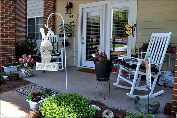 Decorative porch with spring theme, flowers, and rocking chairs.