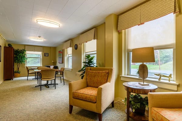 Lounge area with chairs and tables at St. Vincent De Paul Nursing Home.