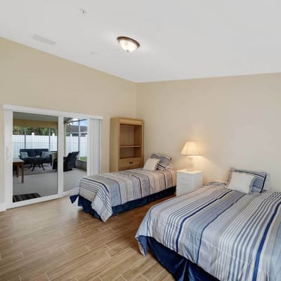 A cozy bedroom with two twin beds and sliding glass doors leading to an outdoor area.