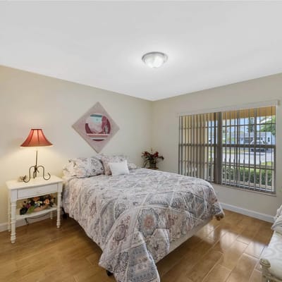 A neatly arranged bedroom with a bed, lamp, and window.