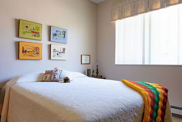 Cozy bedroom with artwork and a colorful blanket