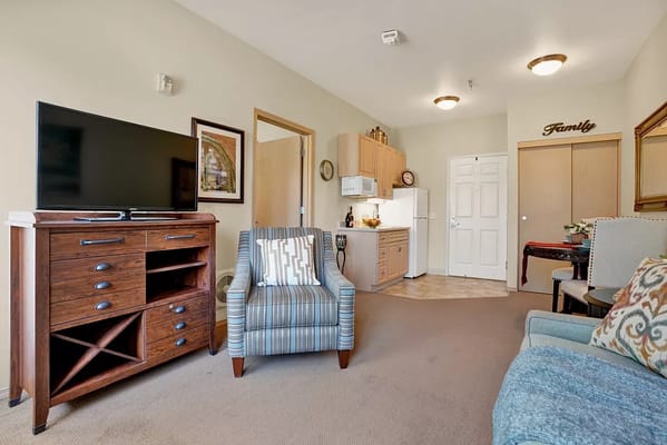 Living room featuring a TV, seating, and kitchen area