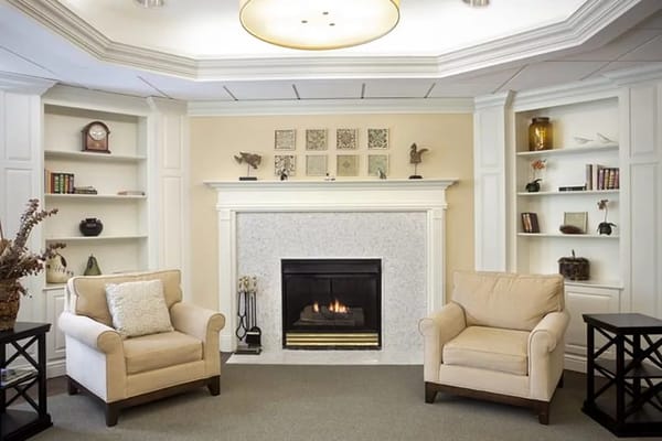 Comfortable living room featuring beige armchairs and a fireplace.
