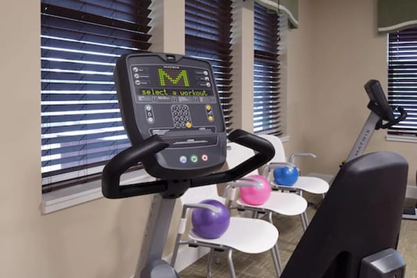 Gym equipment displaying a workout selection screen with colorful kettlebells in the background.