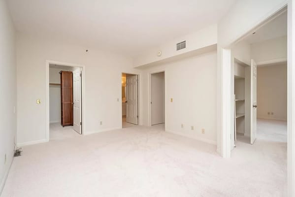 Bright and spacious bedroom with plush carpet and multiple doors