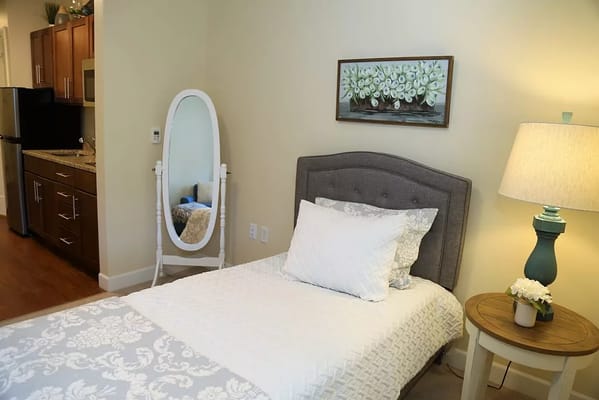 Bright and inviting bedroom with a bed, lamp, and kitchenette