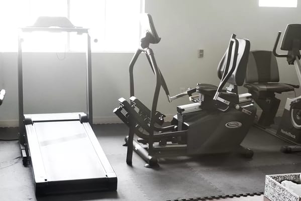 Treadmill and elliptical machine in a senior living gym.