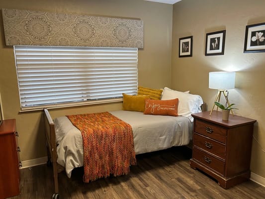 Cozy private room with a bed, decorative blanket, and a side table