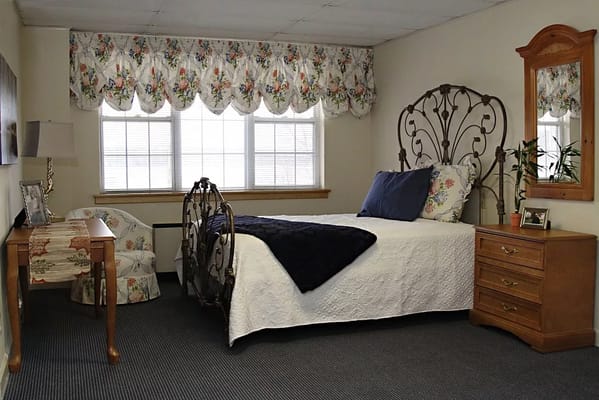 A cozy resident room with a bed and dresser