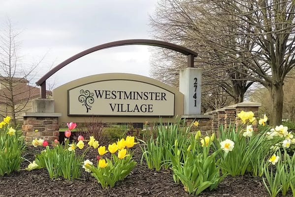 Signage for Westminster Village with blooming flowers