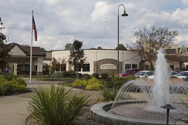 Exterior view of Westminster Village with fountain and flag