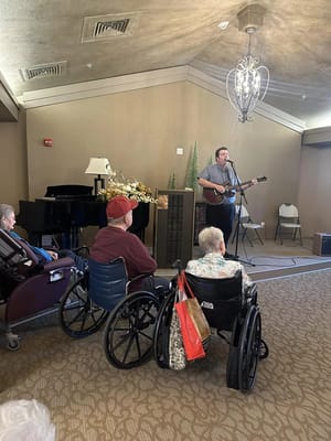A musician performing live in front of residents in a community room.