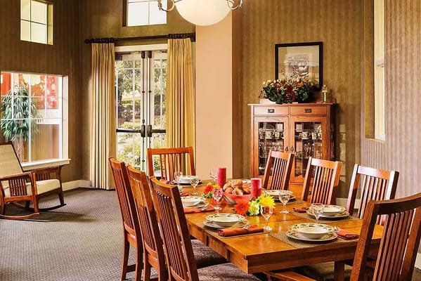 A cozy dining room with a large wooden table set for a meal, featuring chairs and a china cabinet.