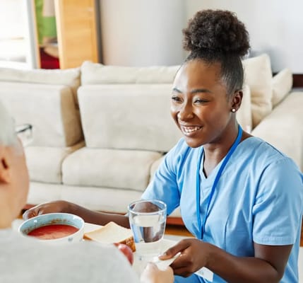 Caregiver serving soup and water to a resident