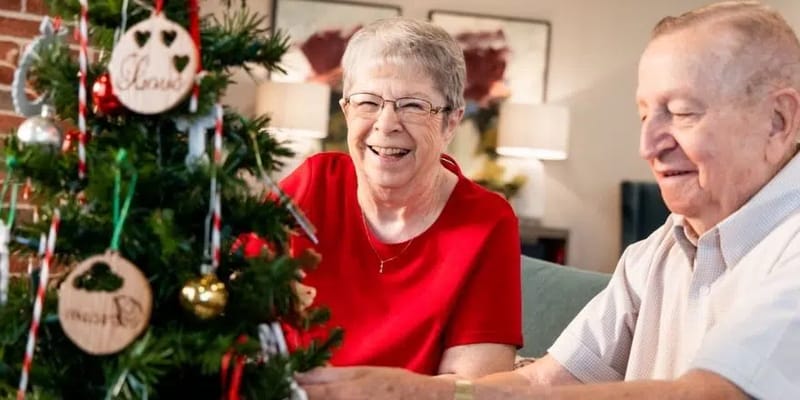 Two residents decorating a Christmas tree together