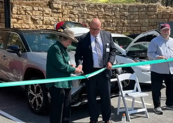 Two people cutting a ribbon at an outdoor event