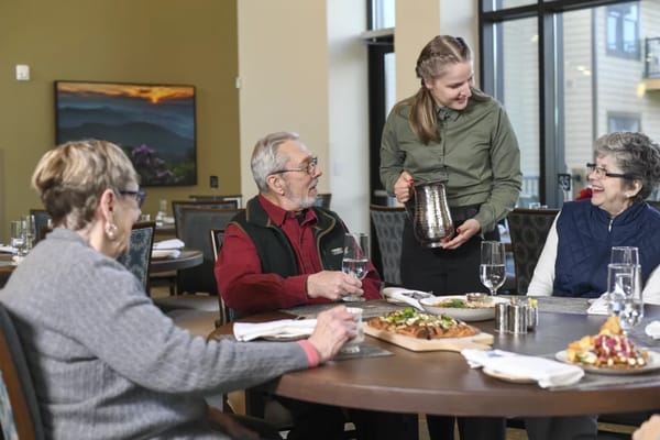 Residents enjoying a meal with staff in the dining area