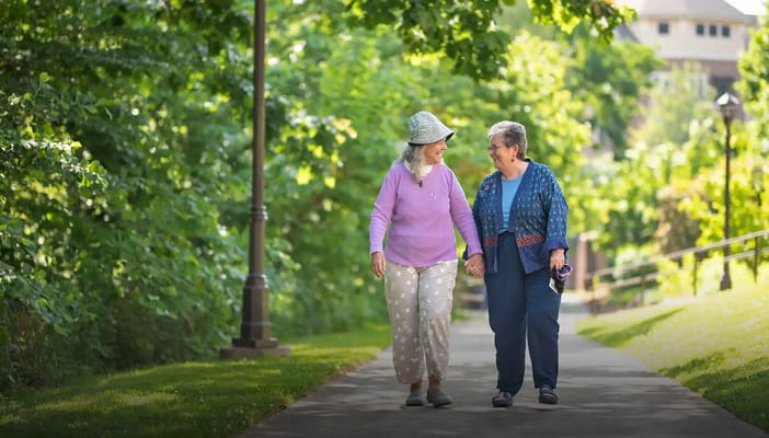 Two residents walking together on a shaded path