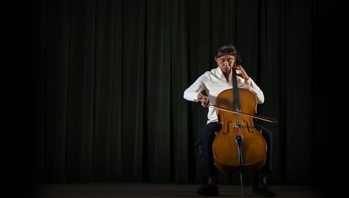 A resident playing cello on a stage