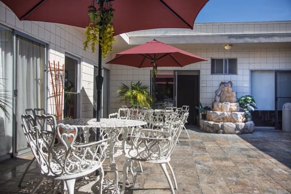 Outdoor patio with white chairs and umbrellas at Sharon Care Center