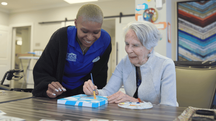 A caregiver assisting a resident with painting