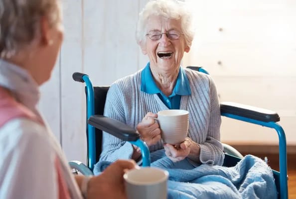 Resident laughing while holding a cup in a bright space