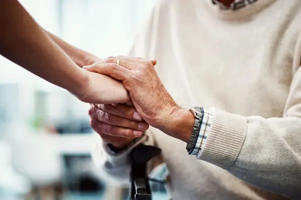 A caregiver holding hands with a resident in a caring gesture