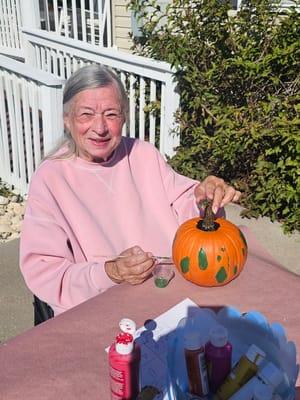 Resident painting a pumpkin outside during an activity