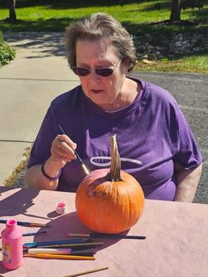 Senior resident painting a pumpkin outdoors