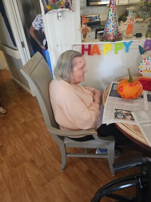 A resident sitting in a common area with a pumpkin decoration