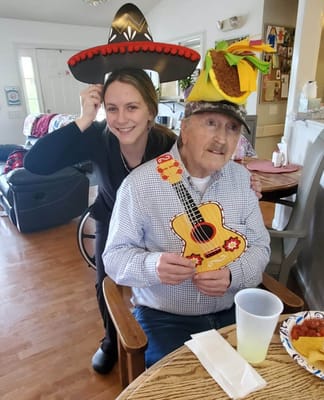 Resident and staff member celebrating with hats and guitar