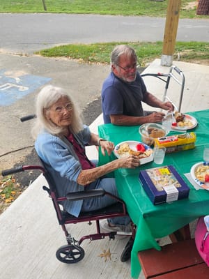 Two residents enjoying a meal outdoors at a table
