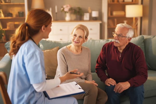 A nursing staff member talking with an elderly couple