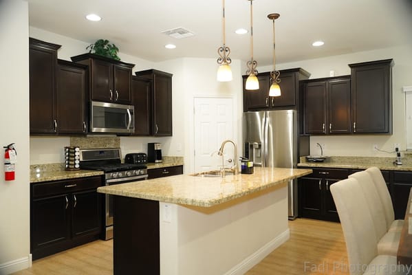 Modern kitchen with dark cabinets and granite countertops.