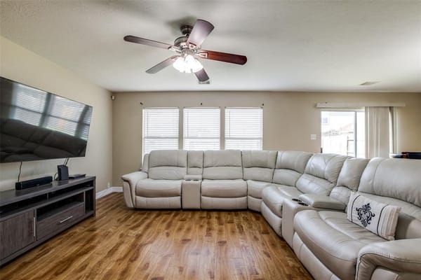 Spacious living room with leather sectional sofa and television in Alia's Assisted Living Facility