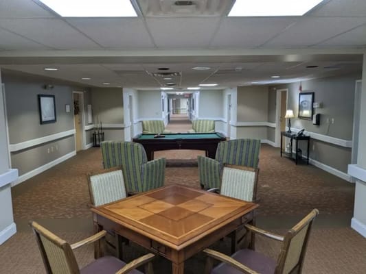 Common area with seating and pool table in a nursing home