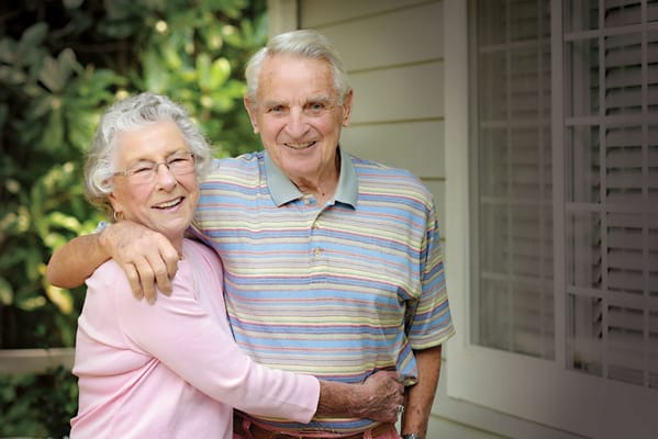 Smiling elderly couple embracing outside a building