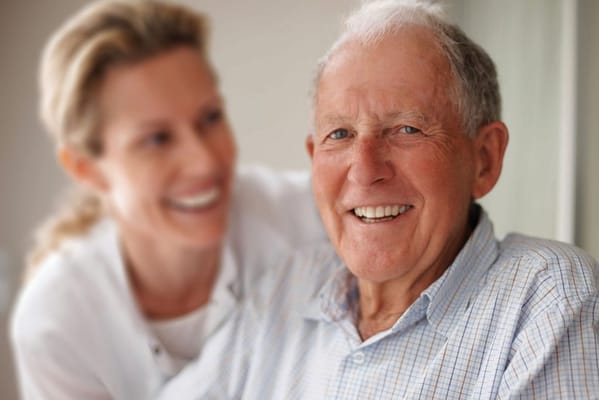 A smiling elderly man with a caregiver