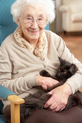Resident smiling while holding a cat in a cozy chair