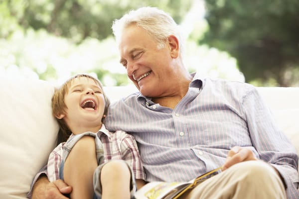 A senior man laughing with a young boy outdoors