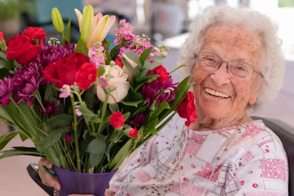Elderly woman smiling with a bouquet of flowers