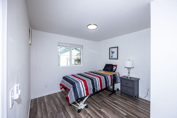 A private resident room with a hospital bed and bedside table