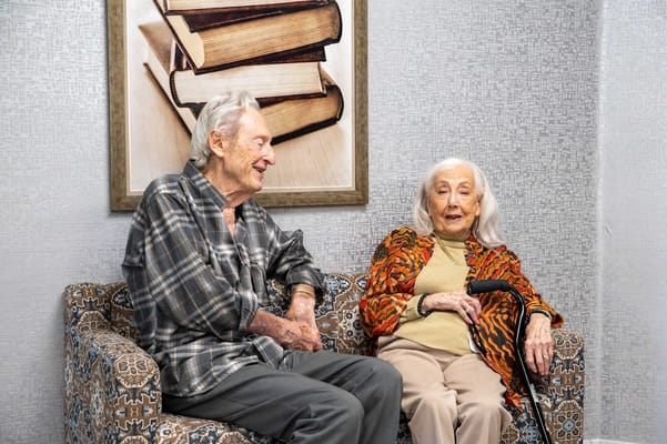 Two elderly residents smiling in a cozy lounge area