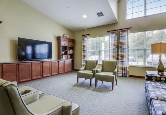 Spacious living room with two chairs, a TV, and large windows