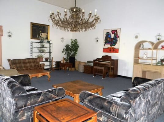 A spacious living room with sofas, a chandelier, and decorative artwork.