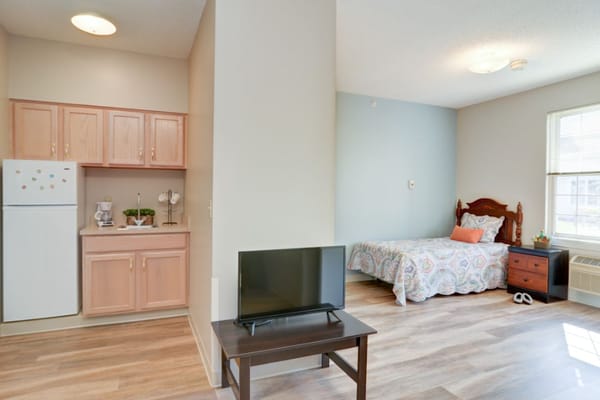 A private resident room with a kitchenette and bed