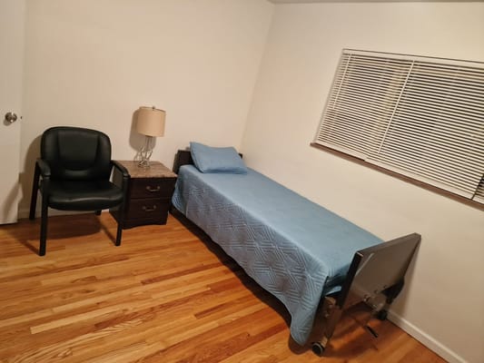 A simple resident room featuring a bed and chair